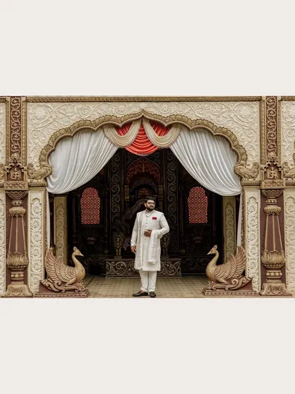 A wide shot of the groom standing proudly in front of the magnificent stage decor. This image captures the scale and grandeur of the engagement ceremony.