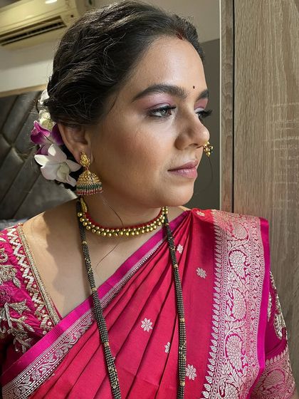 A side view highlighting the soft pink eyeshadow and the elegant braided hairstyle adorned with flowers.