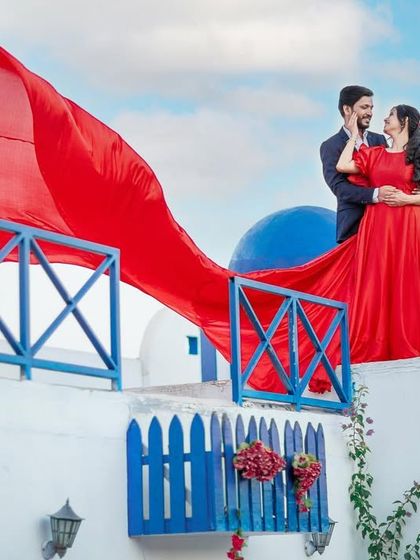 A vibrant shot on the same Santorini set, this time with a flowing red fabric creating a bold and passionate statement.