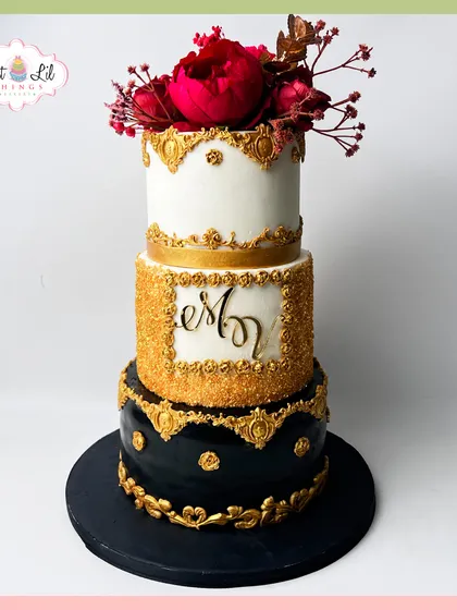 This three-tiered cake is all about drama and luxury. The combination of a deep black bottom tier with intricate gold detailing, a sparkling gold middle tier, and a clean white top crowned with bold red sugar flowers creates a powerful and sophisticated statement, perfect for a milestone birthday or a glamorous event.