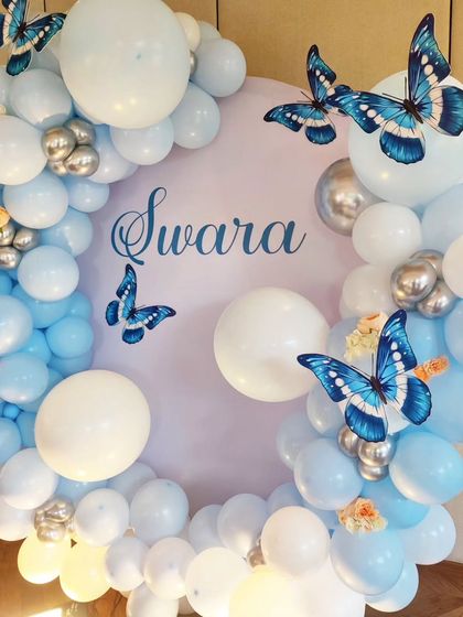 A close-up of a butterfly-themed setup, showing the blue and white balloon arch and butterfly accents.