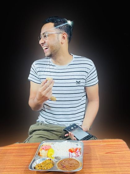 Pure happiness on a plate. A customer is captured mid-laugh while enjoying one of our wholesome thali meals at a table.