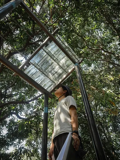 Another view of our team member studying the light quality beneath a roofing sample. These small-scale tests inform our material choices for the final building.
