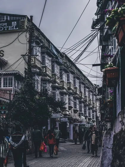 a narrow street in a hill station with a web of wires overhead. this image captures the organized chaos of urban life.