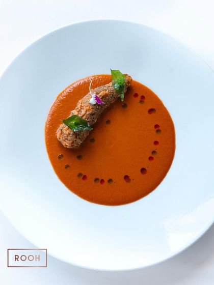 A beautifully composed plate of Prawn 65 with Mangalorean curry. The dish is dotted with chili oil and garnished with a crispy curry leaf, showcasing our attention to detail.