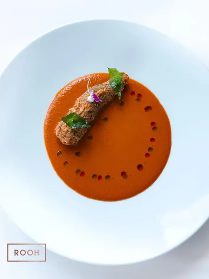 A beautifully composed plate of Prawn 65 with Mangalorean curry. The dish is dotted with chili oil and garnished with a crispy curry leaf, showcasing our attention to detail.
