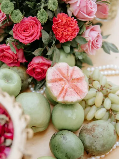 A close-up on the fresh guavas and apples mixed with pink roses, adding a natural and fragrant touch.