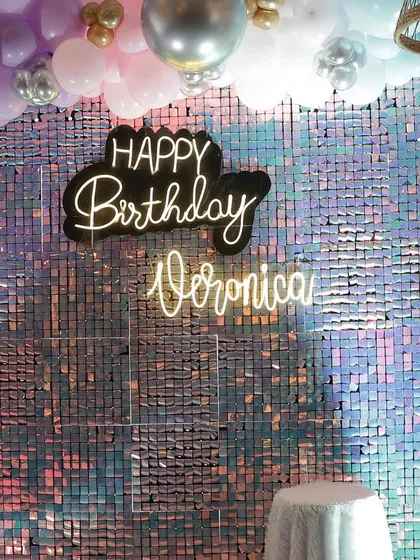 A vibrant and iridescent sequin wall serves as the backdrop for Veronica's 10th birthday. The custom neon sign and pastel balloon arch add a fun, youthful touch to the glamour.