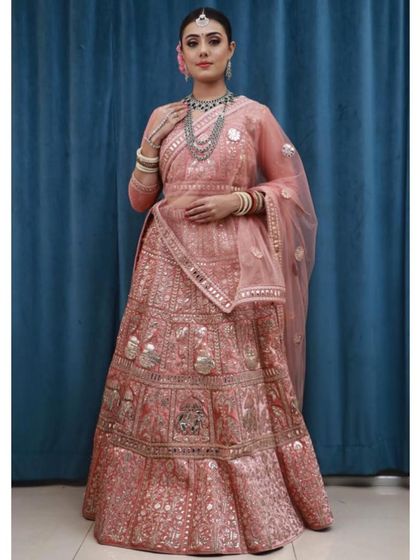 This client looks regal in a peach-pink lehenga featuring traditional gota patti and mirror work. It’s a classic design that is perfect for weddings and festive occasions.
