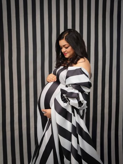 Timeless stripes, reimagined for motherhood. This portrait, with its bold black and white pattern, is a nod to iconic fashion moments, styled to celebrate the beautiful curve of the baby bump.