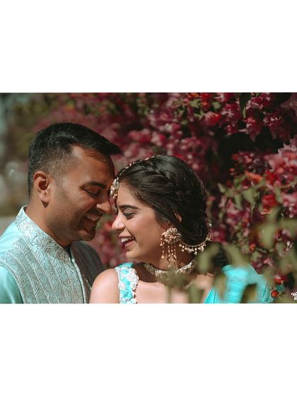 An intimate portrait of the couple surrounded by bougainvillea, capturing a quiet moment of love during their Mehendi festivities.