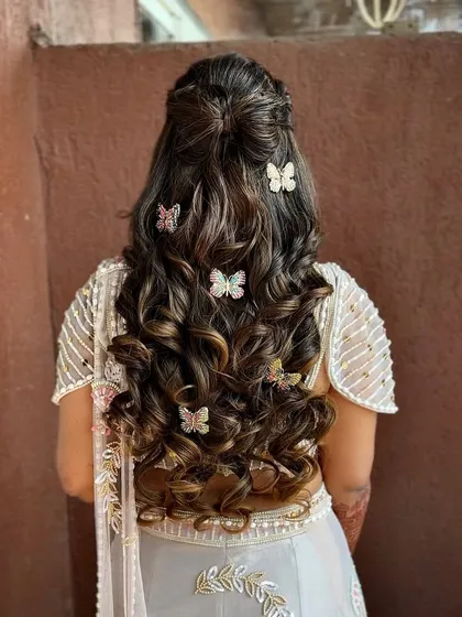 A whimsical half-updo with tight curls, decorated with beautiful butterfly clips.