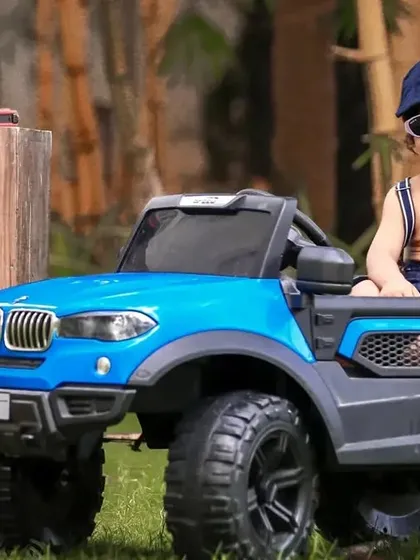A smiling toddler enjoying the driver's seat in our outdoor garage-themed shoot. The sunglasses add an extra touch of cool.