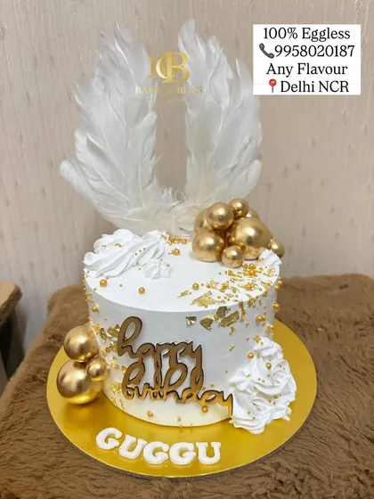 An angelic theme for a special birthday celebration. This cake features beautiful white angel wings as a topper, complemented by gold spheres, gold leaf, and elegant white frosting swirls.