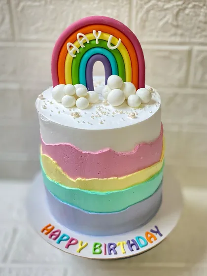 The beautiful pastel layers and fondant rainbow topper on our popular rainbow cake.