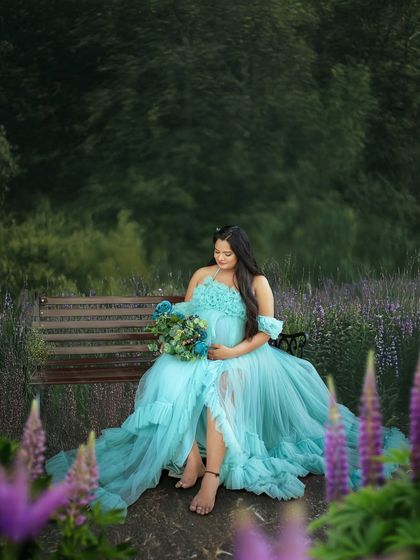 A moment of quiet reflection in a beautiful garden. The flowing blue gown spreads out around her, creating a stunning visual against the purple flowers.