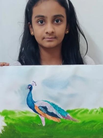 A talented student, Haasvi, proudly holding her finished watercolor painting of a peacock.