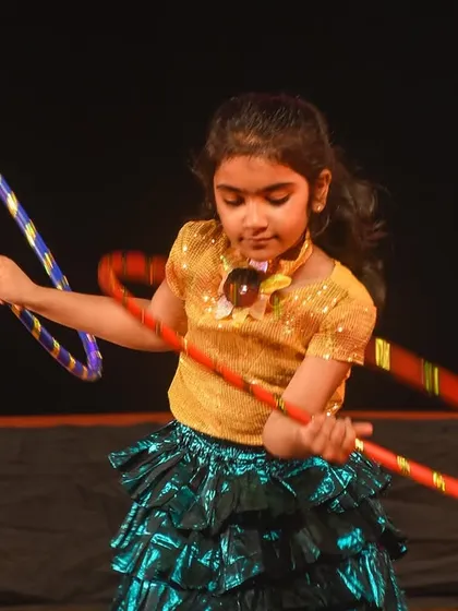 A young performer skillfully manipulates two hoops during her solo moment. This demonstrates our ability to teach specialized skills like hoop dancing for unique and memorable acts.