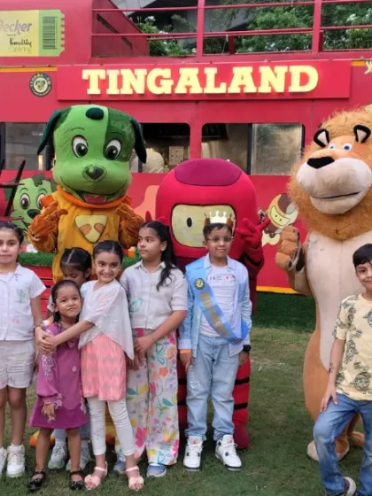 Our mascots aren't just for indoors! Tinga Dojo, Popsy, and friends join a group of kids for a photo in front of our iconic red bus at the outdoor venue.