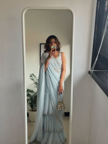 A mirror selfie showing off a beautiful powder blue ruffled saree. This is a great modern take on the classic silhouette, perfect for a cocktail party or reception.