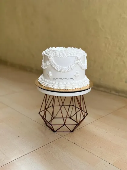 A full view of the white vintage cake with its intricate, hand-piped buttercream details.