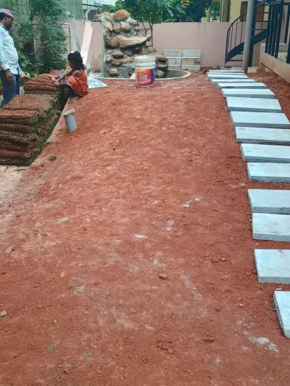 The process continues with laying down stone pavers for a new walkway and preparing to install rolls of fresh turf. You can see the new garden layout taking shape.