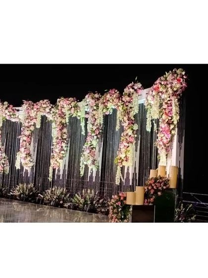 A close-up of the floral and crystal details on the reception stage. The combination of pink and white flowers with shimmering strings creates a look of pure opulence.