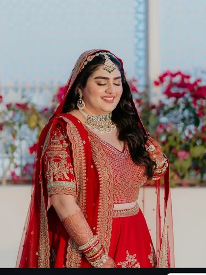 Our bride basking in the sun. The natural light highlights the soft, elegant makeup and the intricate details of her red lehenga.
