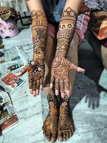 A complete bridal look with matching mehendi on the hands and feet. The designs feature traditional peacock and jaali patterns for a coordinated and beautiful finish.