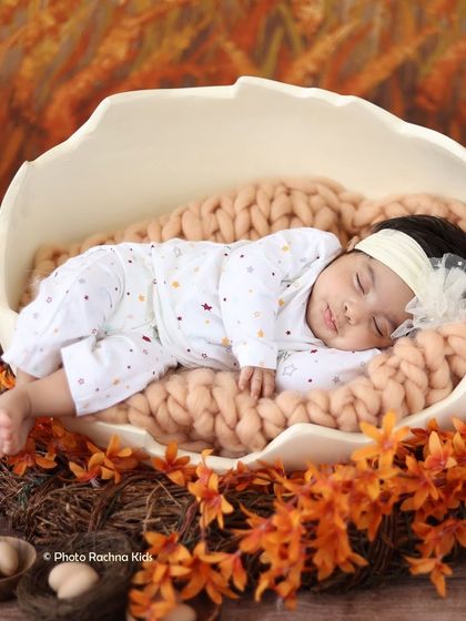 A closer shot of the newborn in the autumn-themed egg setup, capturing their peaceful sleep.