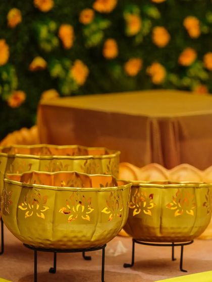 Intricate golden bowls used as part of the traditional Haldi ceremony decor, set against a backdrop of marigold flowers.