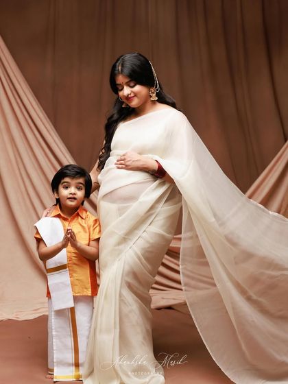 A beautiful maternity portrait celebrating the upcoming arrival. The older sibling-to-be joins in, dressed in traditional attire, adding a layer of cultural richness and family anticipation.