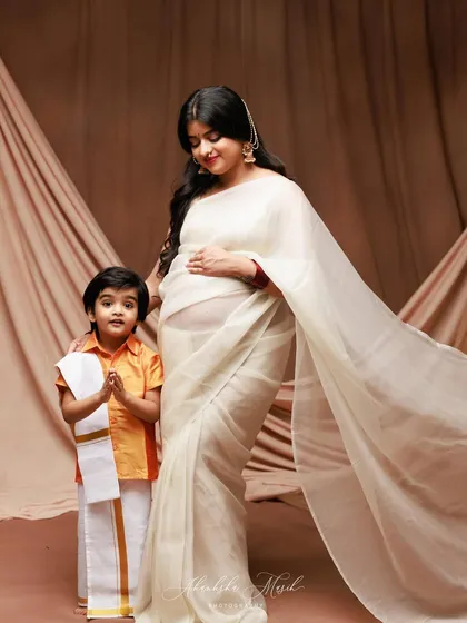 A beautiful maternity portrait celebrating the upcoming arrival. The older sibling-to-be joins in, dressed in traditional attire, adding a layer of cultural richness and family anticipation.