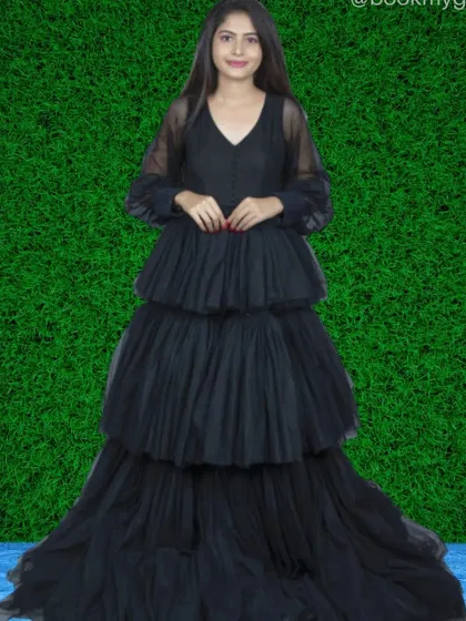 For a touch of modern elegance, this black tiered net gown is a perfect choice. Its sheer long sleeves and layered skirt offer a chic and sophisticated silhouette for any event.