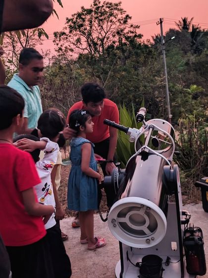 An instructor guides a young girl and her family, helping them find planets and stars. Our small group sizes ensure everyone gets a personal and engaging astronomy experience.