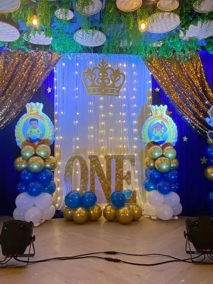 A royal Prince theme for a first birthday, using a blue, white, and gold color scheme with a crown motif and sequin drapes.
