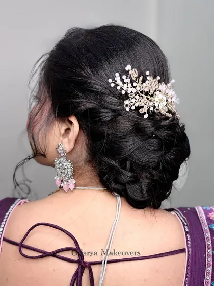 A beautiful and intricate low bun, perfect for a reception or engagement. The braided details and delicate crystal hairpiece add a touch of modern elegance.