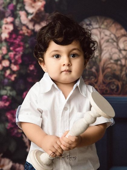This little guy holds a prop, looking directly at the camera with his big, beautiful eyes.