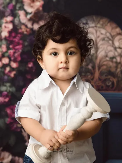 This little guy holds a prop, looking directly at the camera with his big, beautiful eyes.