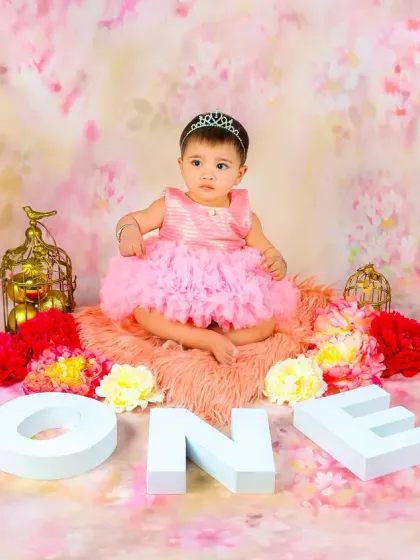 A baby girl dressed as a princess for her first birthday, sitting next to large "ONE" letters. A classic and beautiful way to mark this special milestone.