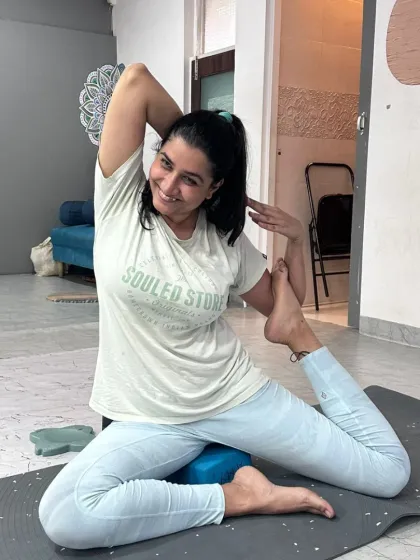 A student uses a block under her hip for support in Pigeon Pose, a modification that makes the deep stretch more manageable and beneficial.