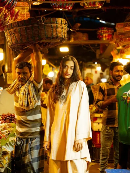 A candid shot capturing the model in the middle of a busy market scene. This documentary-style approach tells a story of the place and the person.