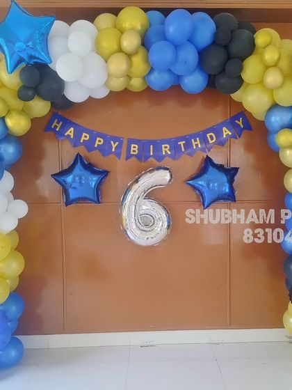 A bike racing themed balloon arch in blue, yellow, and black for a 6th birthday celebration.