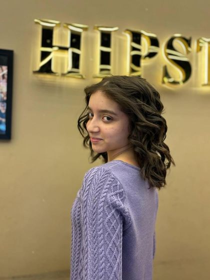 A side view of a young client's curly hairstyle, a look that is both adorable and chic.