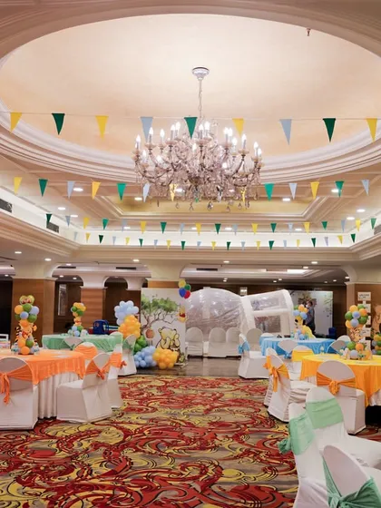 A wide view of the banquet hall decorated for the Winnie the Pooh party, showing the themed table settings and colorful bunting flags hanging from the ceiling.