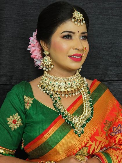 A smiling portrait of the bride in her green and red saree. The makeup is fresh and radiant, perfect for a daytime wedding ceremony.
