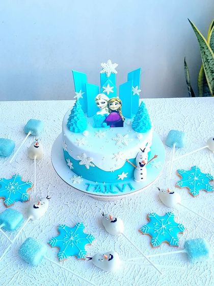 A Frozen-themed dessert table, including a cake, Olaf cakepops, and snowflake cookies. This shows how to carry a theme across different types of treats.