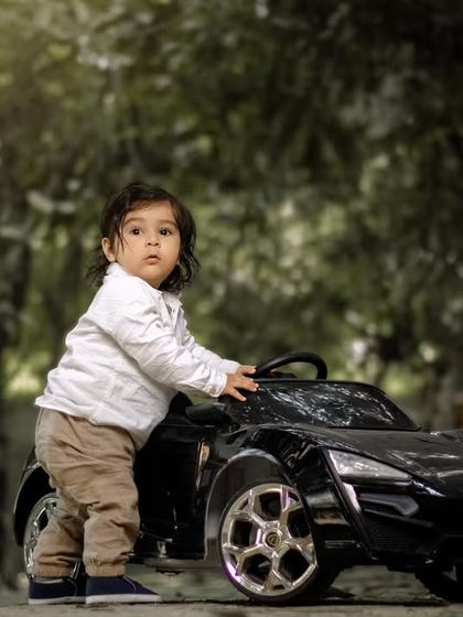 Capturing the essence of pure joy. A toddler stands by his toy car on a wooded path.