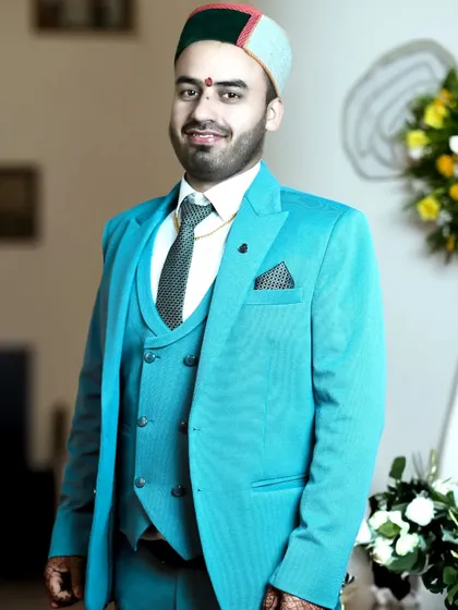 A smiling groom portrait, capturing a moment of happiness and excitement. The combination of formal wear and cultural headwear is beautifully showcased.