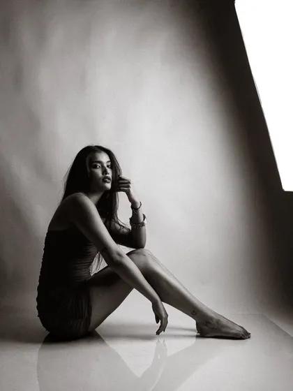 A moody, low-key black and white studio portrait. The single light source creates a dramatic, sculptural effect.